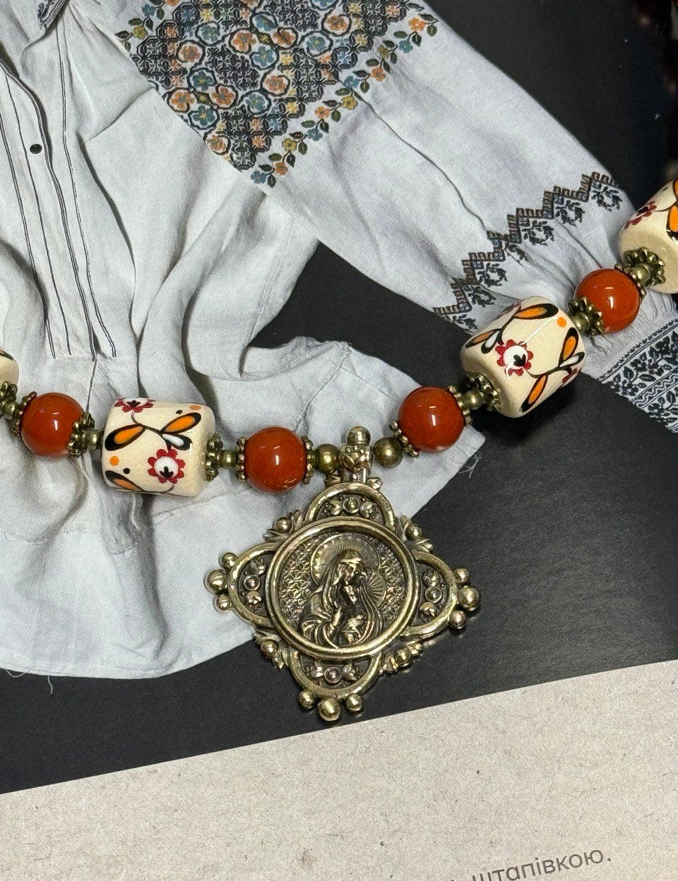 Ukrainian handmade necklace with white clay and jasper beads, featuring traditional designs and cultural symbols.