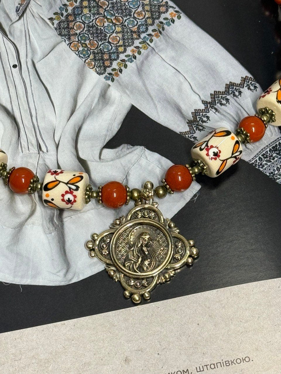 Ukrainian handmade necklace with white clay and jasper beads, featuring traditional designs and cultural symbols.