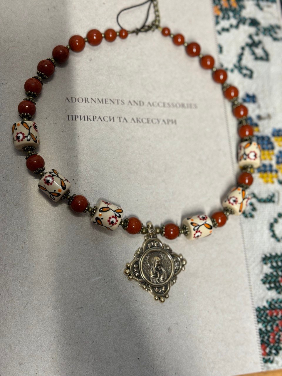 Ukrainian handmade necklace with white clay and jasper beads, featuring a cast brass pendant. Inspired by harmony and nature.
