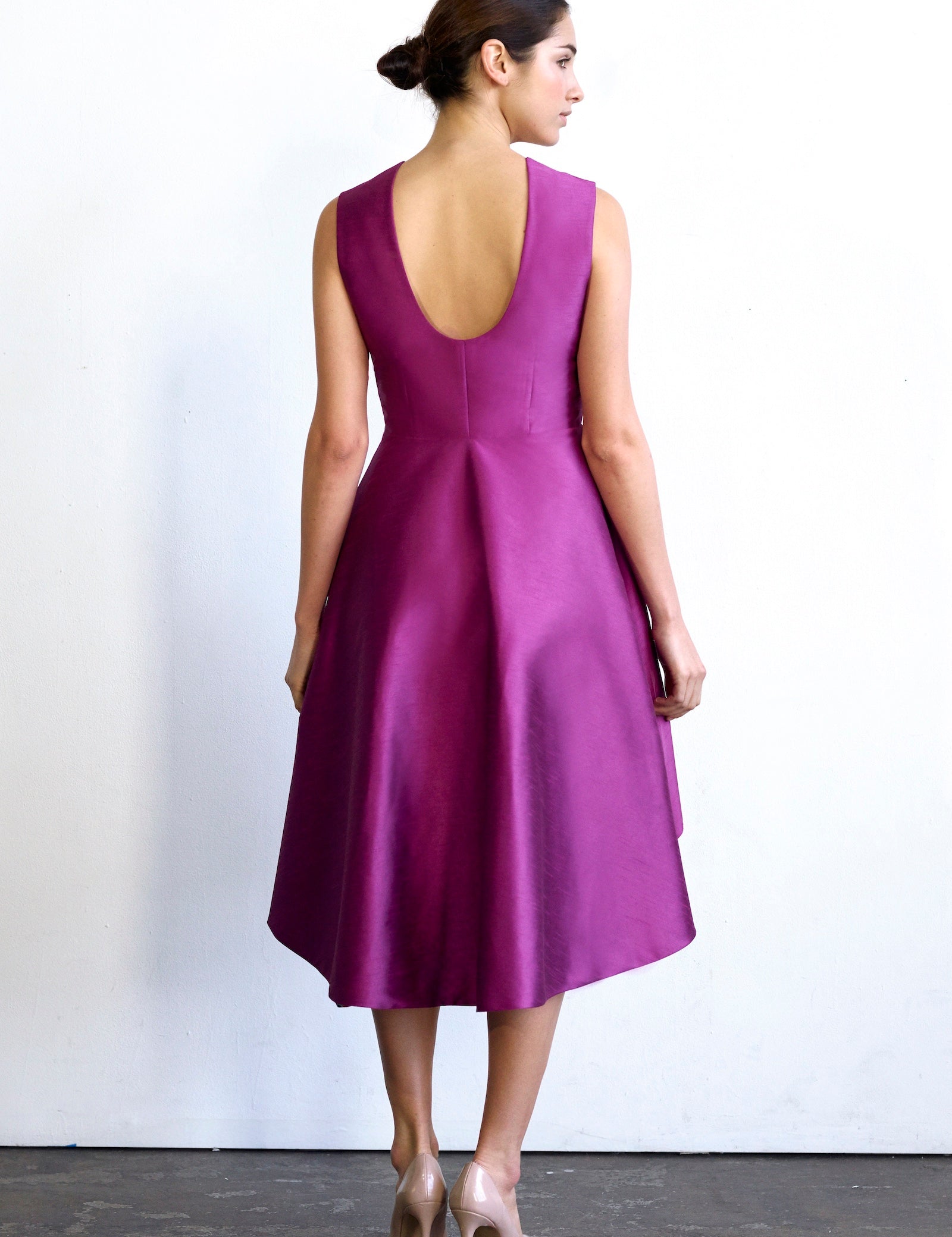 Woman wearing Eliora Open-Back Pink Hi-Lo Dress with U-shaped back and vibrant lining, showcasing elegance and sophistication.