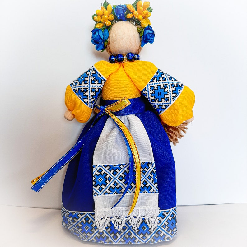 Handmade Ukrainian folk doll in traditional blue and yellow national clothing with embroidery and floral headpiece.