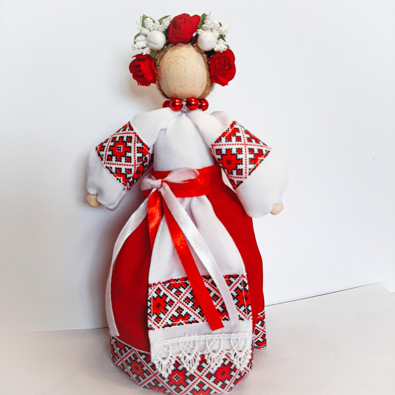 Handcrafted Ukrainian folk doll in traditional red embroidered dress and floral headdress, symbolizing cultural heritage.