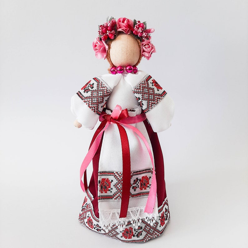 Handcrafted Ukrainian folk doll in traditional dress with floral embroidery and pink accents.