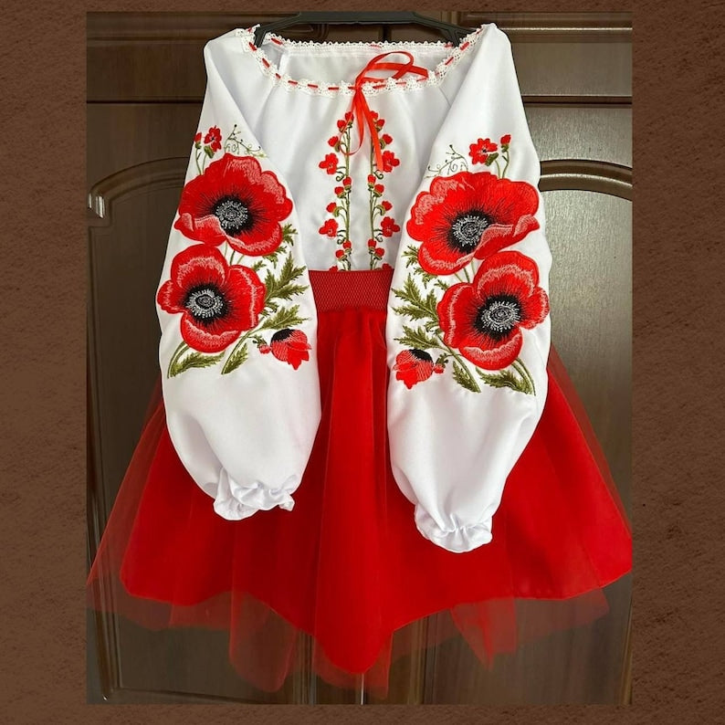 Girl’s Ukrainian embroidered suit with red Vyshyvanka blouse and skirt featuring traditional floral ornamentation.