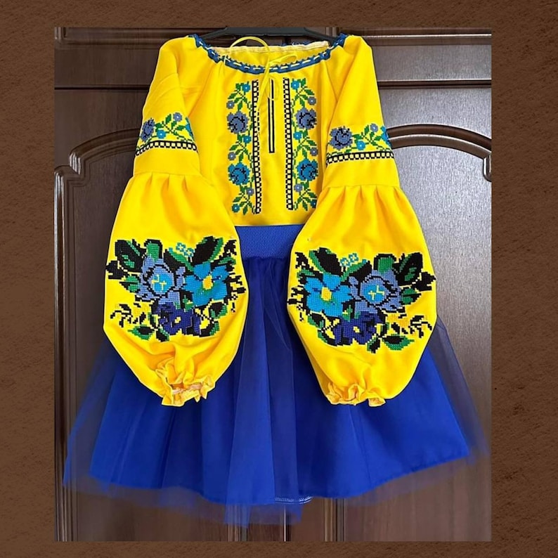 Girl’s Ukrainian embroidered suit with Vyshyvanka blouse and skirt featuring traditional ornamentation in blue and yellow.