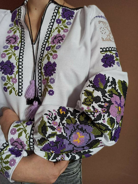 White Vyshyvanka blouse with purple floral embroidery, Ukrainian traditional design on homespun fabric.