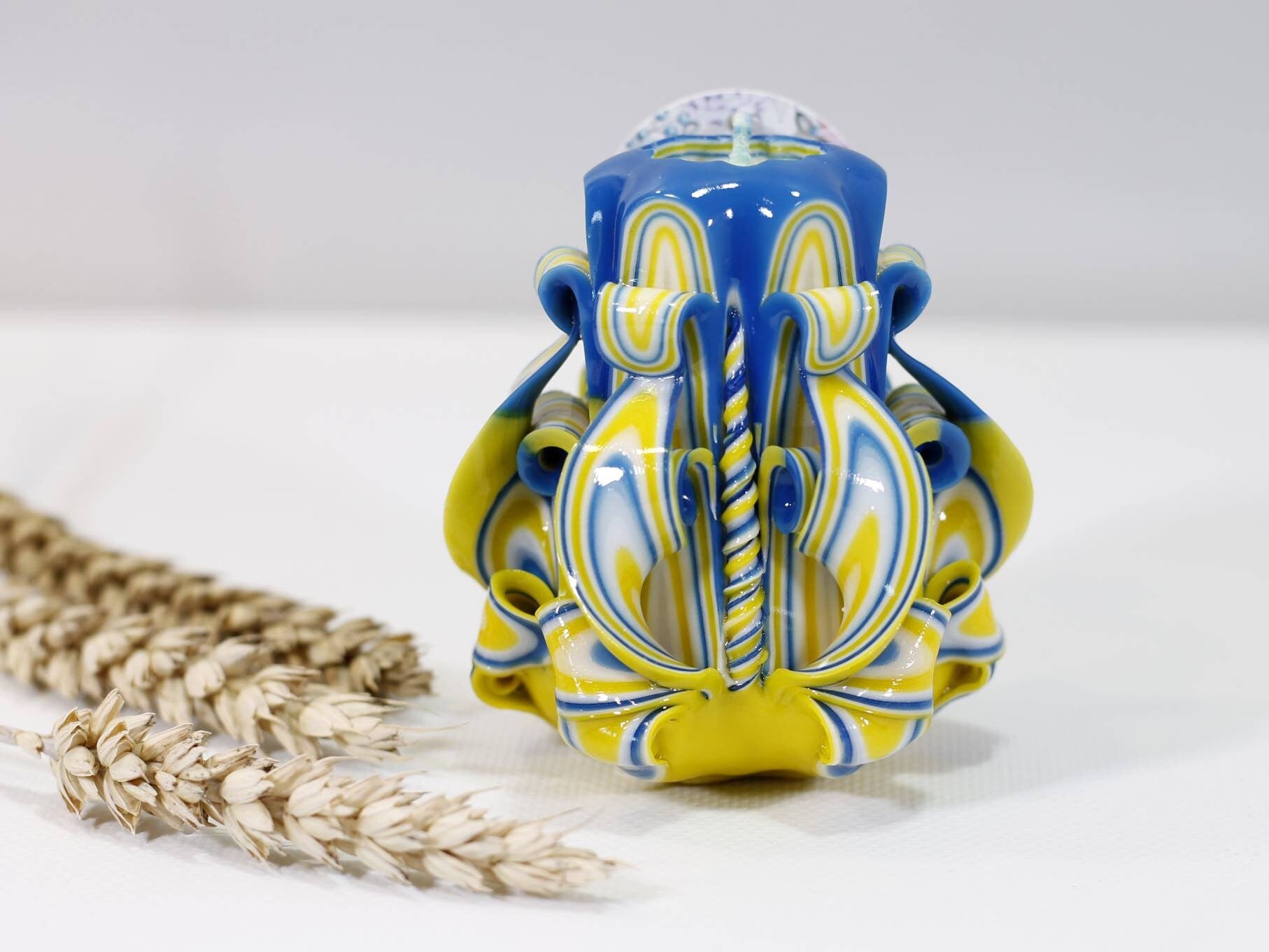 Handcrafted blue and yellow carved candle featuring elegant design, supporting Ukraine with proceeds aiding displaced families and refugees.