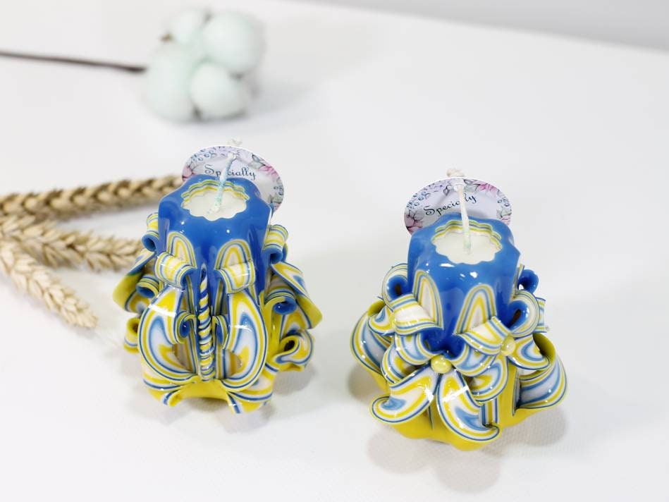 Handcrafted blue and yellow carved candles symbolizing support for Ukraine, with intricate designs and vibrant colors.