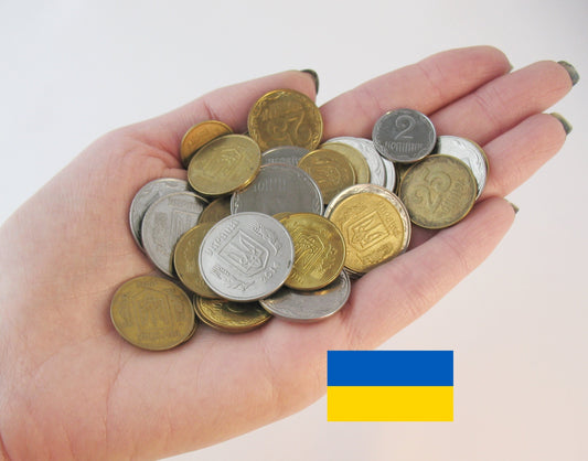 Hand holding a collection of Ukrainian coins with Ukrainian flag, showcasing unique collectible coins.