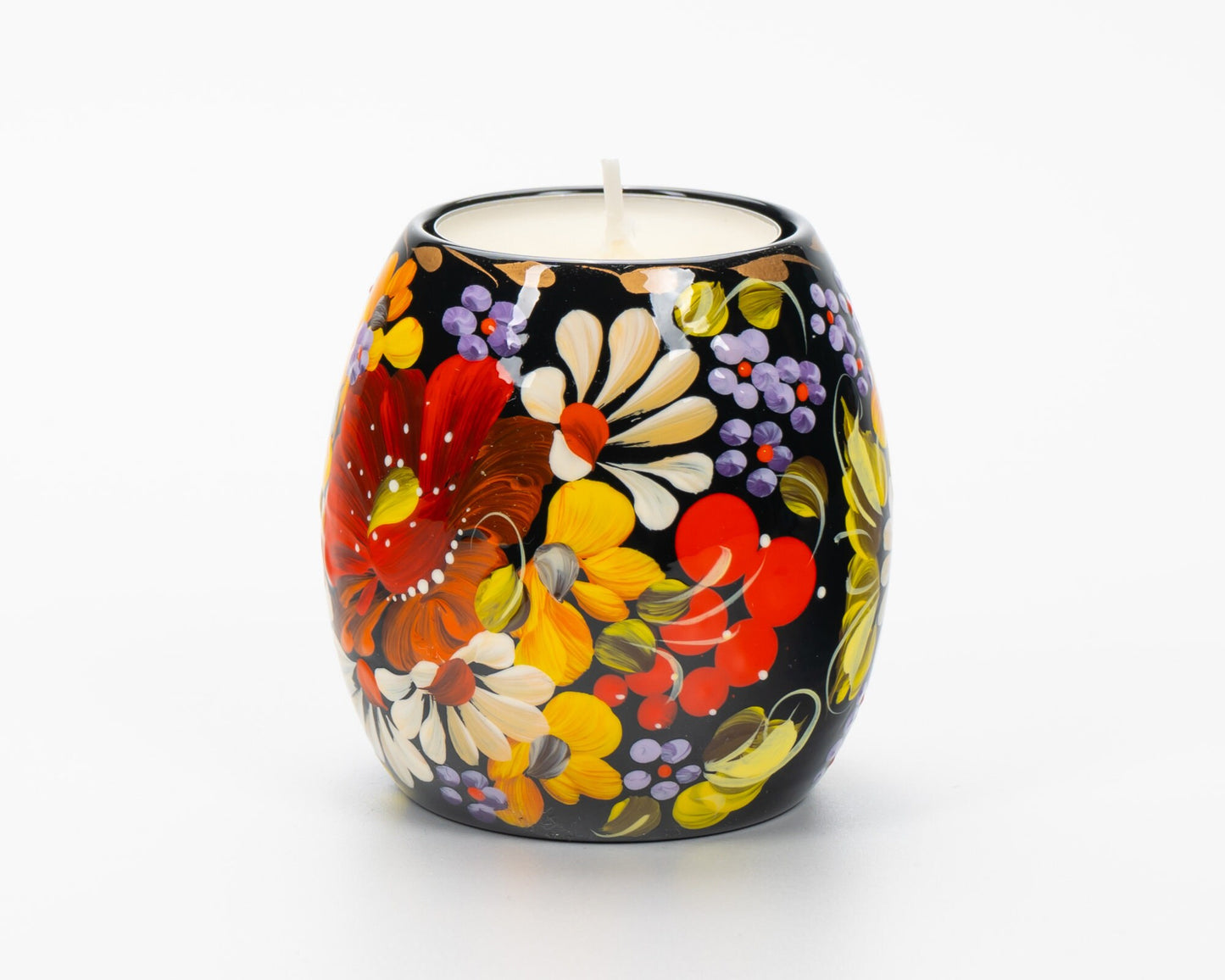 Hand painted tea light candle holder with vibrant Petrykivka floral design on a black background.