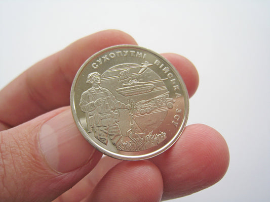 Person holding Ukrainian 10 Hryvnia commemorative coin, 2021, featuring Land Forces of Ukraine design.