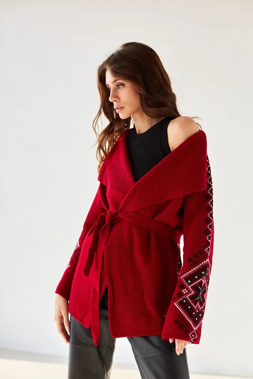 Woman wearing red boho knit cardigan with Ukrainian ornaments, featuring an oversized wrap design for winter warmth.