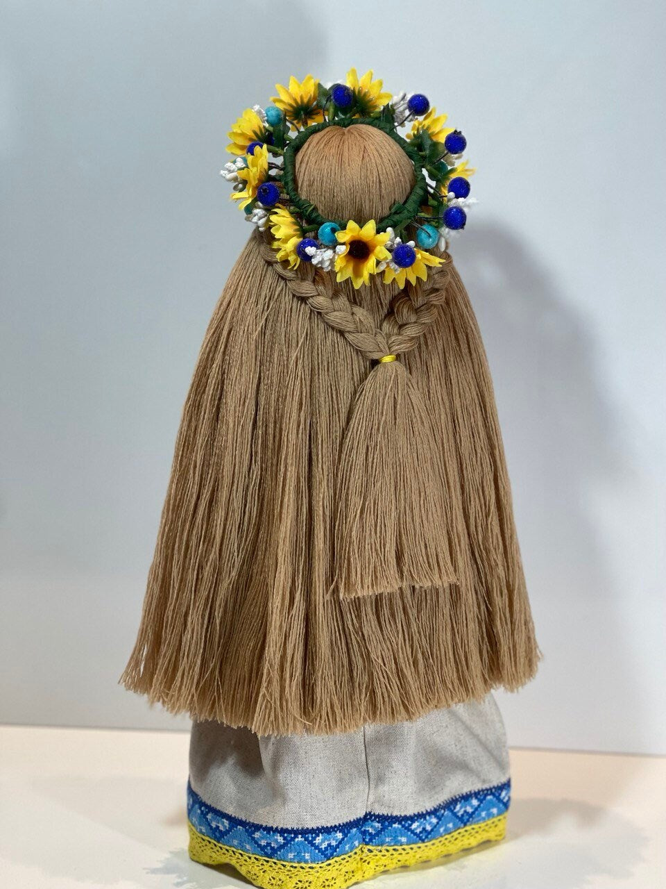 Handcrafted Ukrainian Motanka doll with embroidery and floral headdress on a wooden stand, symbolizing well-being and prosperity.