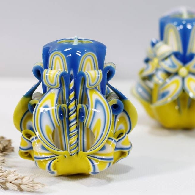 Handcrafted blue and yellow carved candle supporting Ukraine, intricate design symbolizing hope and unity.