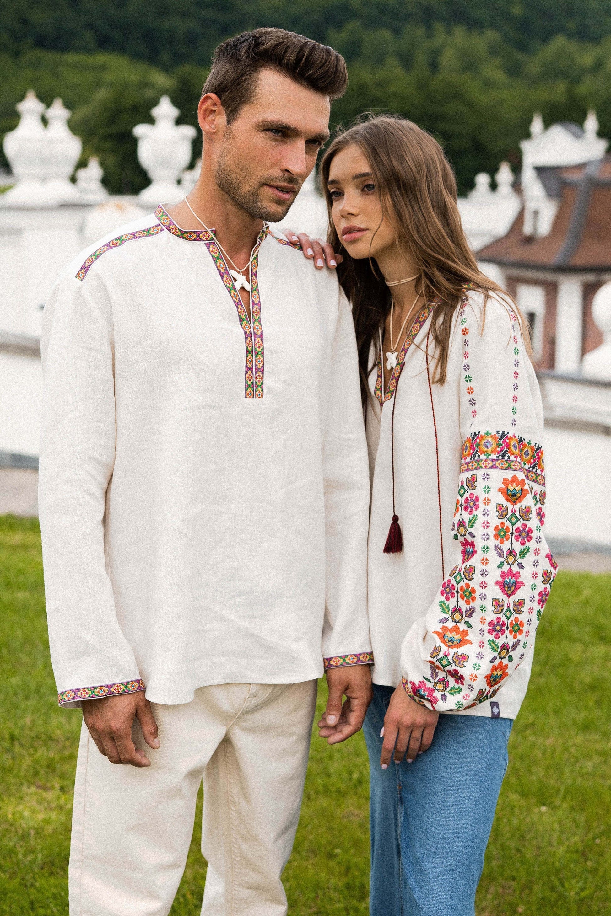 Couple wearing traditional embroidered Ukrainian Vyshyvanka blouses with colorful floral and geometric patterns, standing outdoors.