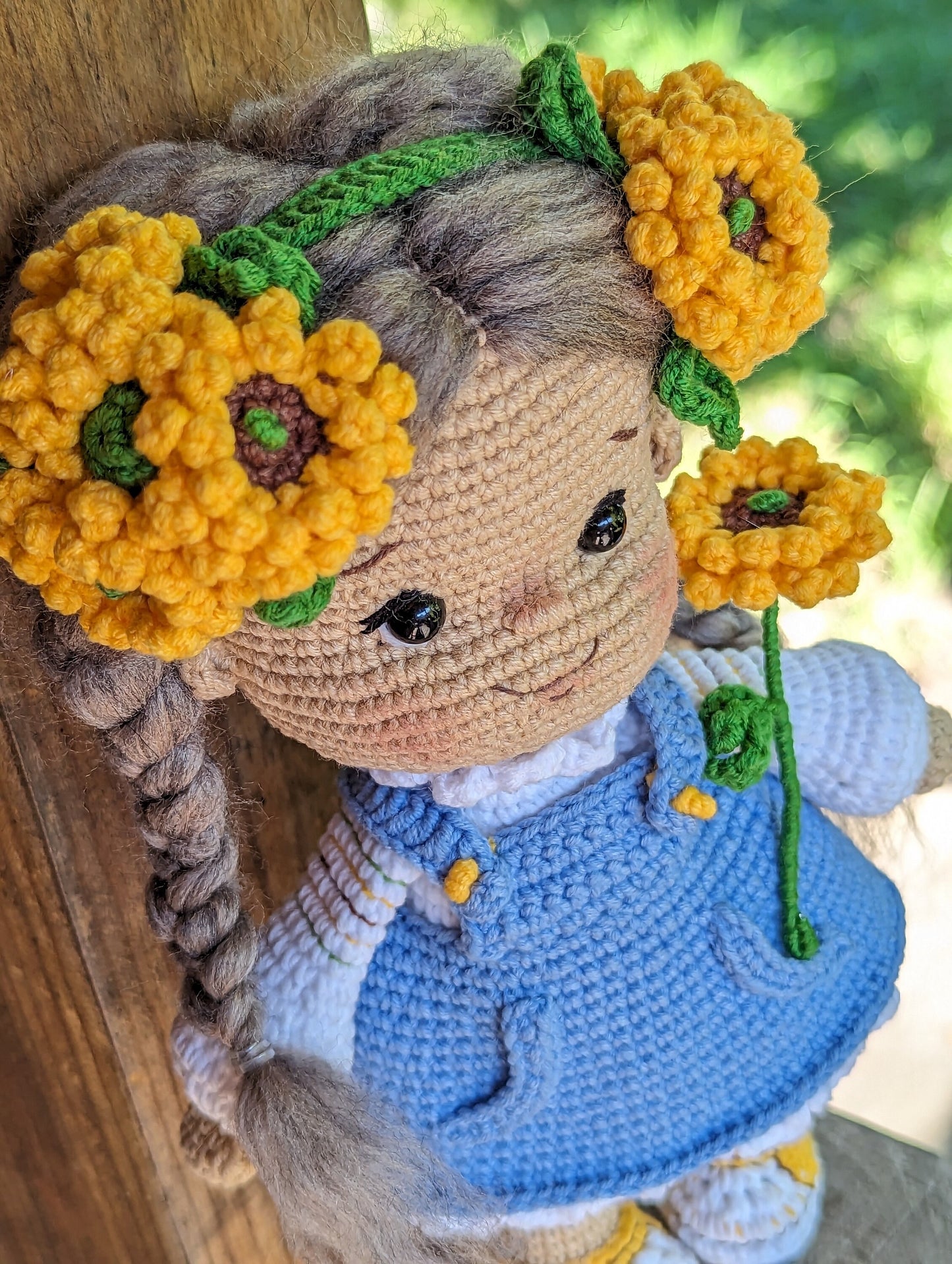 Handmade crochet Ukrainian doll with yellow flower headband in blue dress, cultural folk-style soft toy for nursery decor or gift.