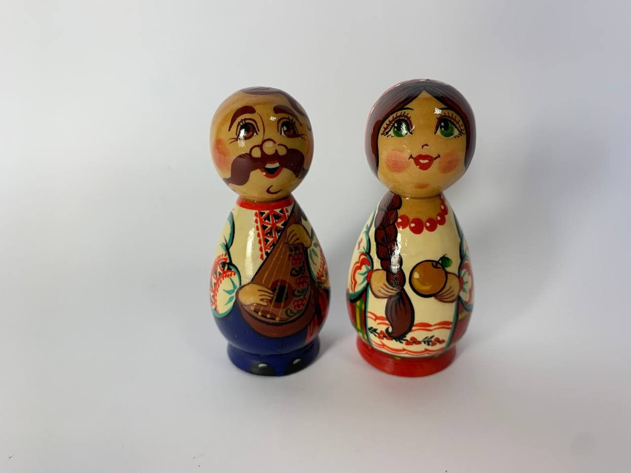 Hand-painted wooden figurines of Ukrainian folk couple, Kozak and girl, showcasing traditional art and vibrant cultural details.