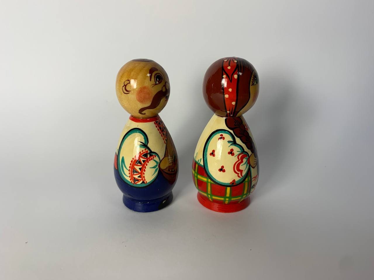 Hand-painted wooden Kozak and girl figurines, showcasing Ukrainian folk art with vibrant traditional designs.