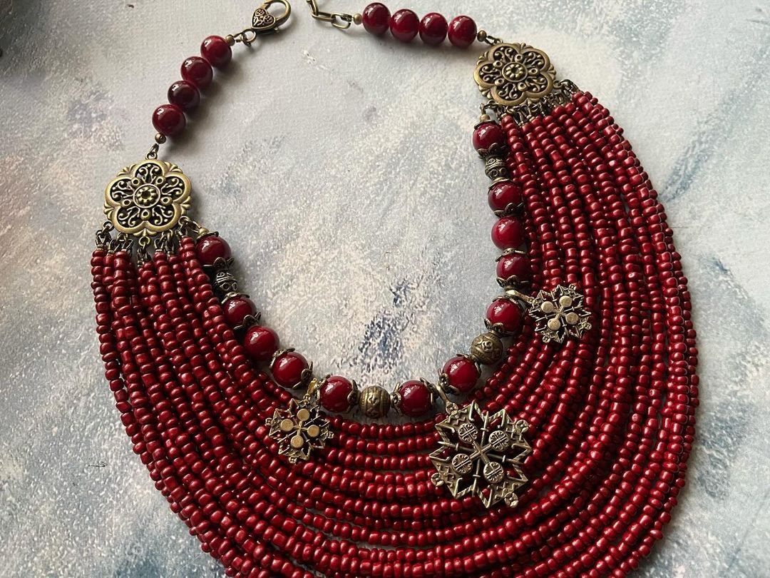 Handmade red Ukrainian multi-row necklace with glass beads and intricate metal fittings, showcasing traditional ethnic jewelry design.