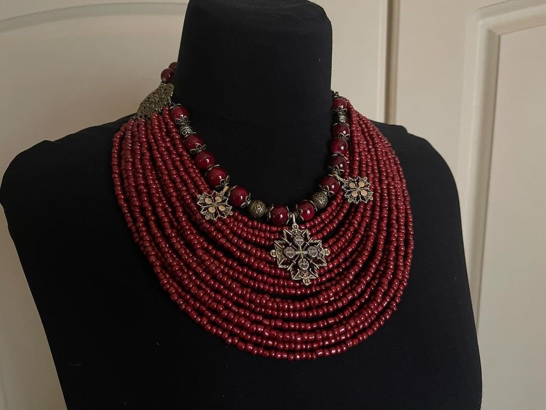 Handmade red Ukrainian multi-row necklace with glass beads and intricate metal accents, showcasing traditional ethnic jewelry design.