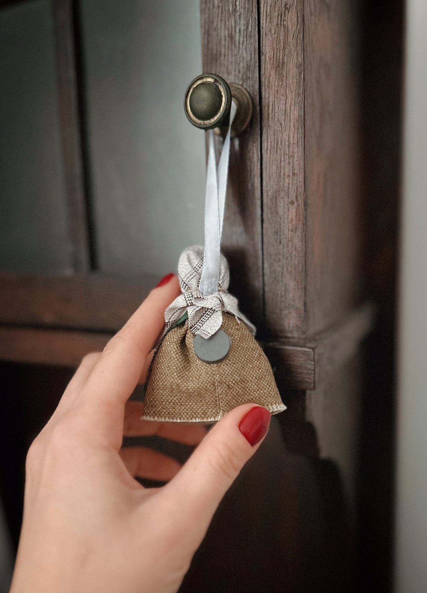 Handmade Ukrainian doll charm on cabinet knob, showcasing Motanka craft as a unique home decor piece with a symbolic horseshoe.