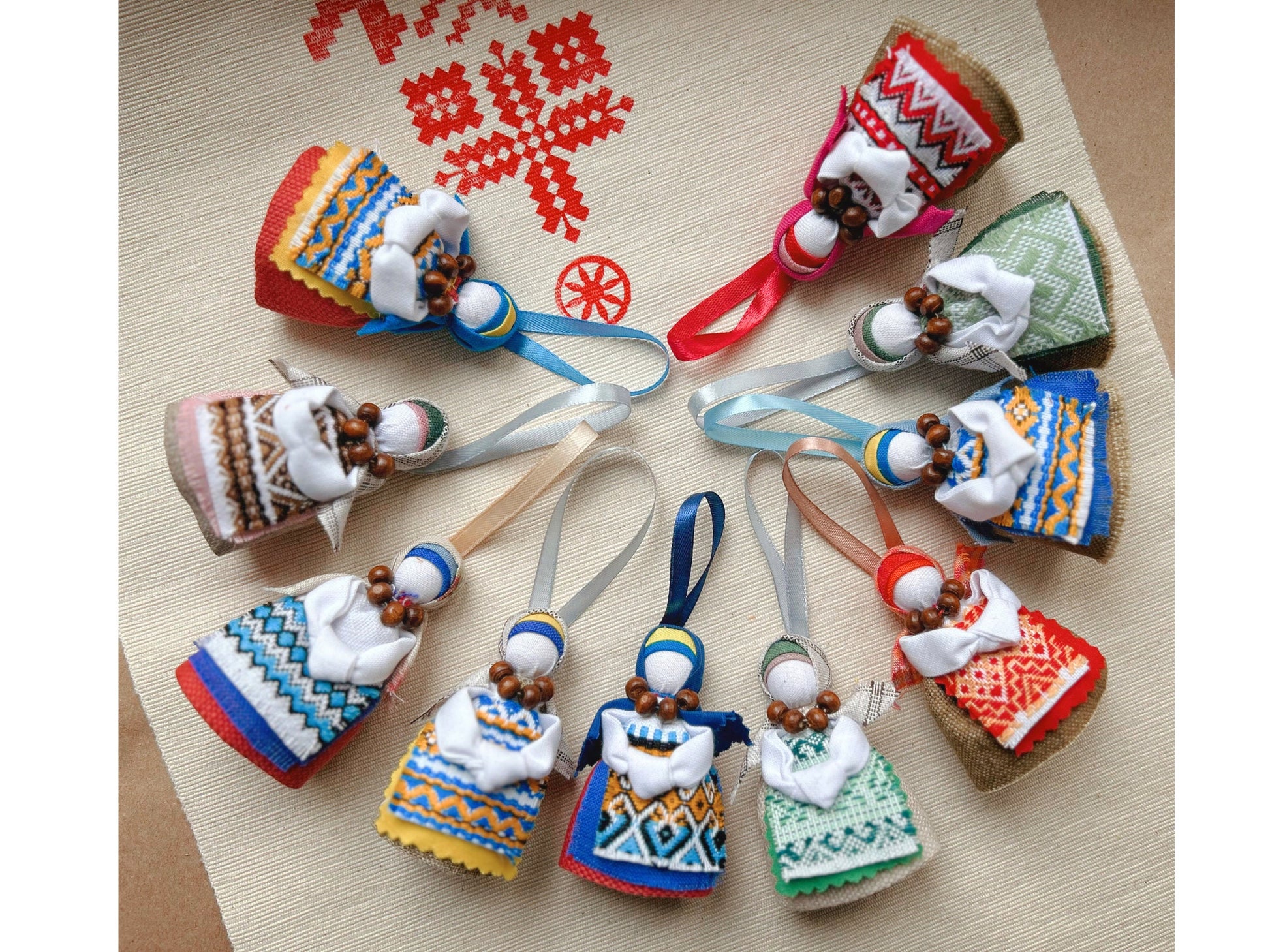 Colorful Ukrainian Motanka dolls arranged in a circle on a decorative cloth background.