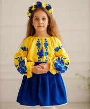 Girl wearing Ukrainian embroidered blouse and skirt set in blue and yellow, featuring floral designs, traditional outfit for cultural celebrations.