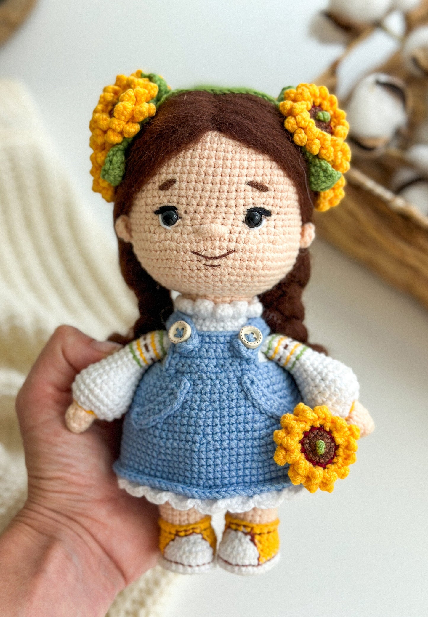 Handmade Ukrainian themed knitted doll with sunflowers, soft and cozy gift item, held in hand.