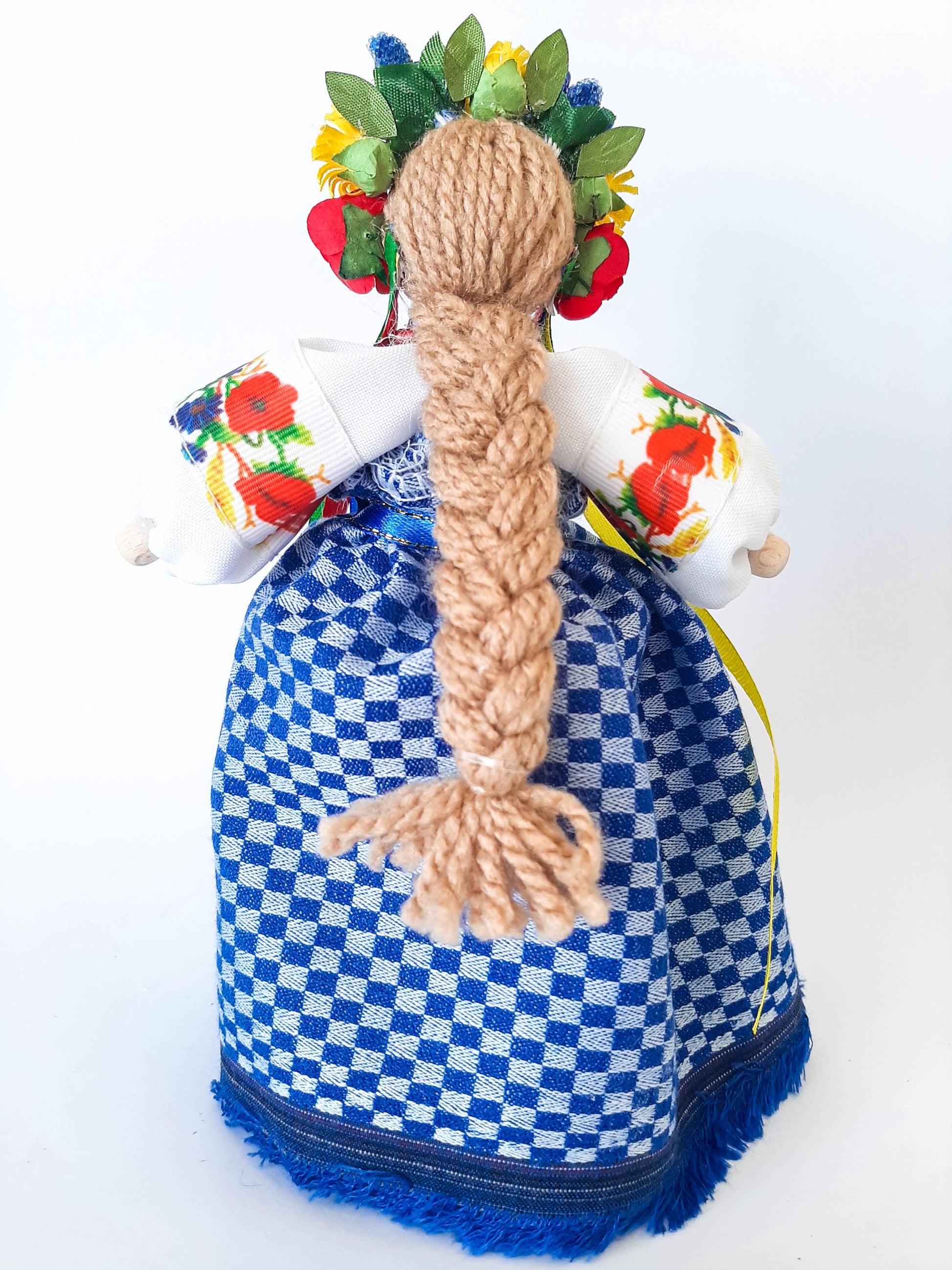 Ukrainian Motanka doll with floral crown and blue checkered dress, symbolizing protection and prosperity, perfect housewarming gift.