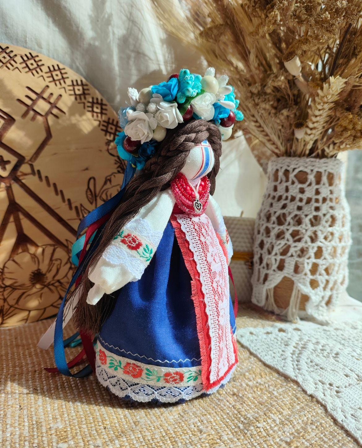 Handmade ethnic motanka doll with floral headpiece, embroidered dress, symbolic of tradition and charm, 17-18 cm tall.