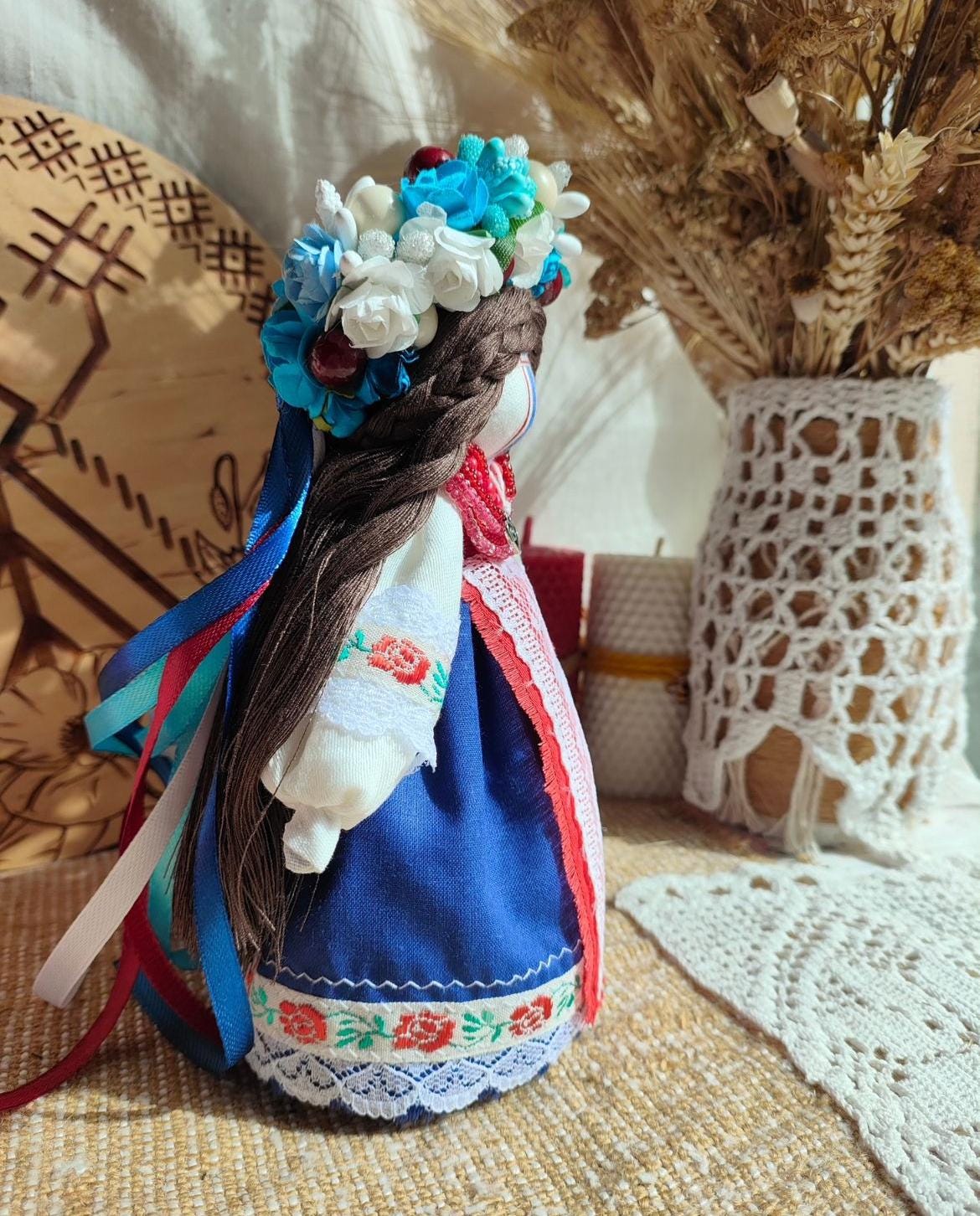 Handmade ethnic Motanka doll with floral headdress, symbolizing tradition and protection, displayed in a cozy home setting.