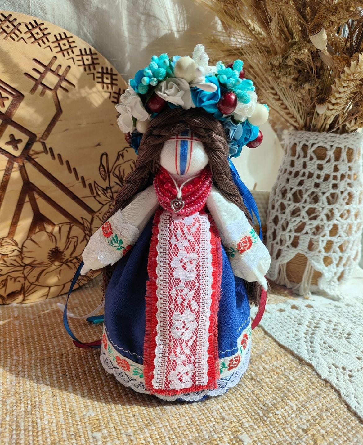 Handmade ethnic Motanka doll with colorful floral headdress, symbolizing protection and tradition, on a textured background.