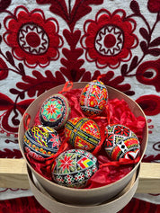 Set of 6 hand-painted Ukrainian Pysanky Easter eggs in vibrant colors, featuring traditional folk symbols and patterns, in a bowl.