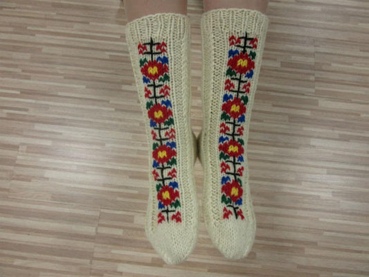 Folklore knitted wool socks with vibrant embroidery on wooden floor, cozy winter gift for men and women.