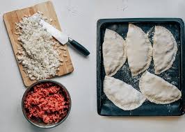 Preparing homemade Ukrainian chebureki with beef filling and chopped onions ready for baking.