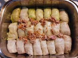 Rows of homemade Ukrainian holubtsi, traditional stuffed cabbage rolls with meat and rice, in a baking dish, ready to serve.