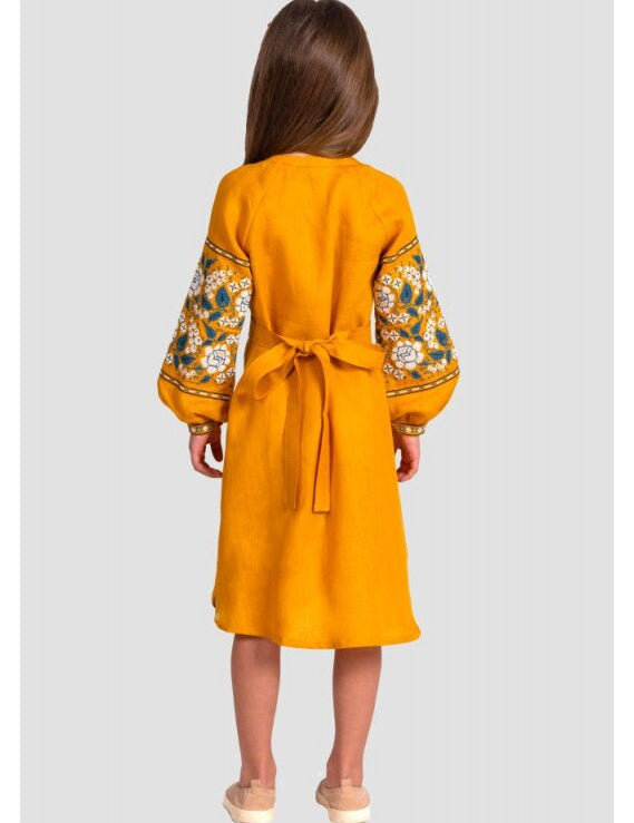 Rear view of a girl in a mustard linen Vyshyvanka dress with floral embroidery, showcasing long sleeves and a tie belt.