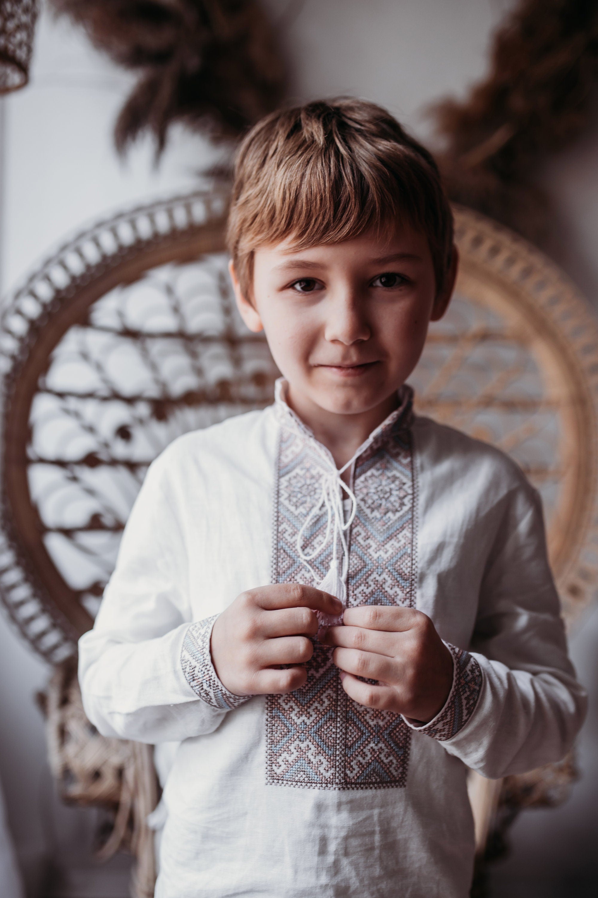 Boy wearing Ukrainian embroidered Vyshyvanka shirt with traditional cross-stitch pattern in brown and blue.