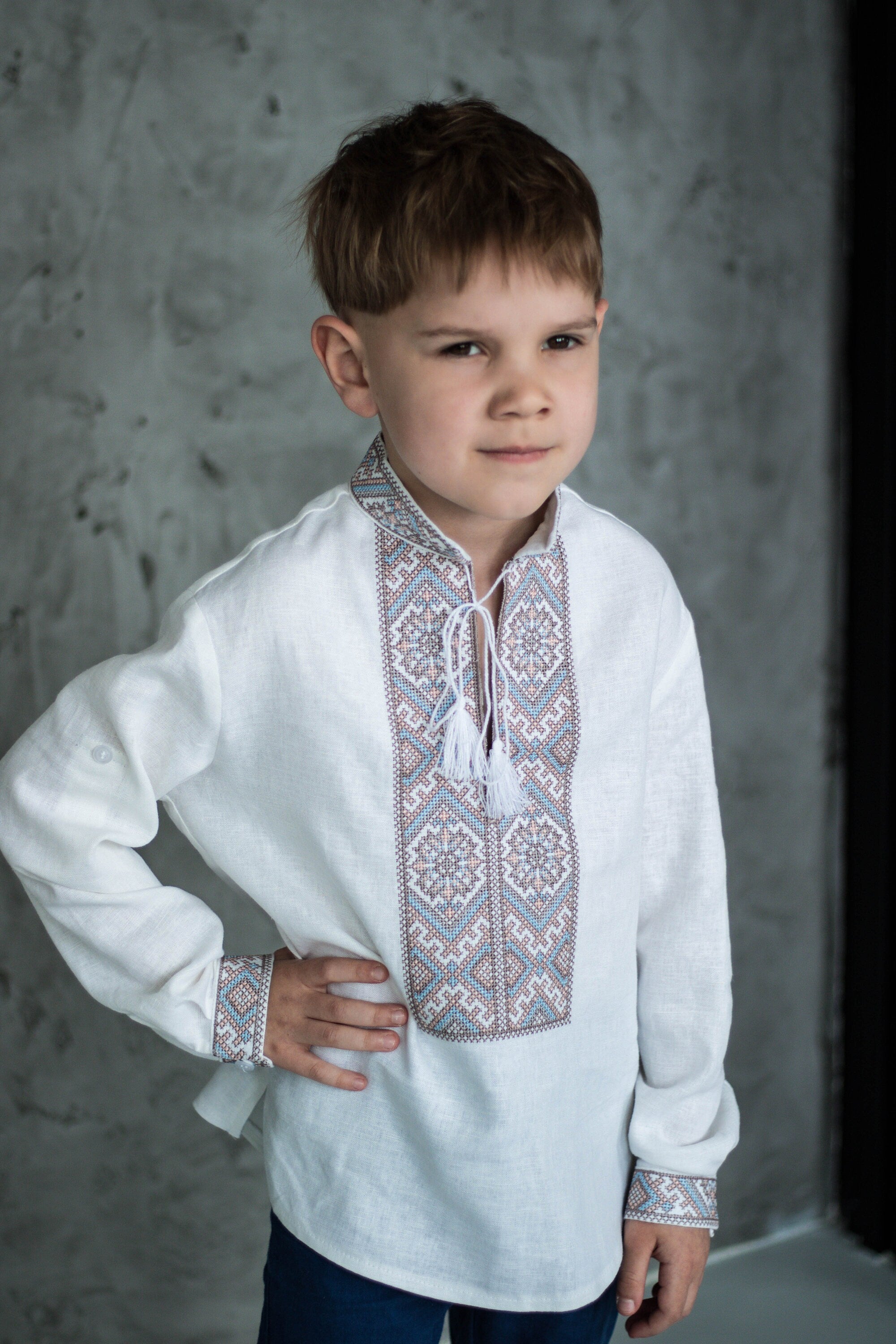 Boy wearing Ukrainian Vyshyvanka shirt with brown and blue geometric embroidery pattern.