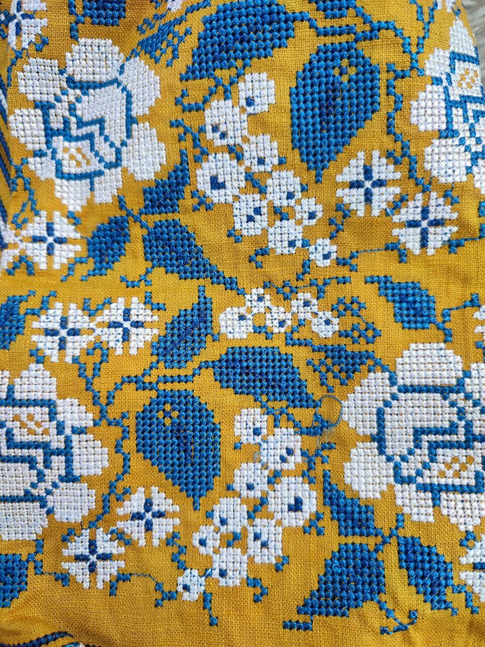 Detail of floral embroidery on mustard linen Vyshyvanka dress for girls, showcasing traditional Ukrainian folk patterns.