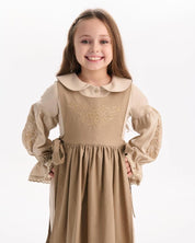 Girl wearing a Ukrainian linen embroidered dress with Slavic folk motifs, featuring puff sleeves and a peter pan collar.