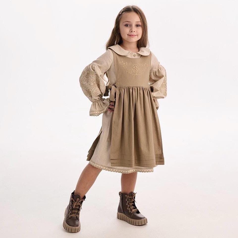 Little girl wearing a Ukrainian embroidery dress in Slavic ethnic style, showcasing traditional folk motifs. Linen-cotton blend fabric.