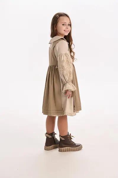 Young girl wearing a beige linen embroidered dress in Ukrainian Vyshyvanka Slavic style, showcasing intricate folk patterns.