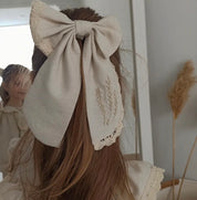 Child wearing a comfortable linen dress with embroidered bow, showcasing natural elegance and charm, perfect for warm weather.