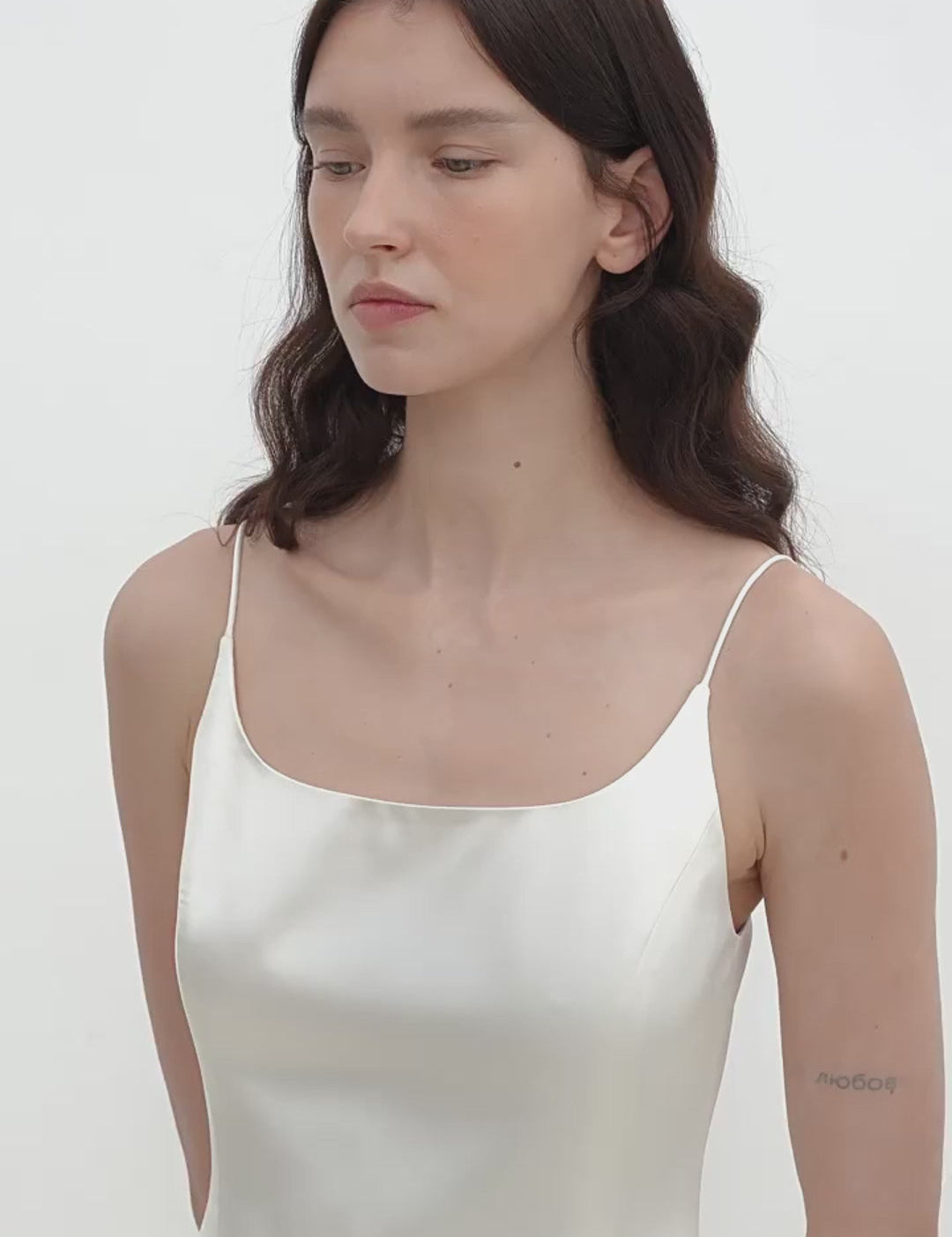 Woman wearing Lyrielle Satin Ballet Slip Dress with slender straps and glossy finish, showcasing elegant ballet-inspired silhouette.