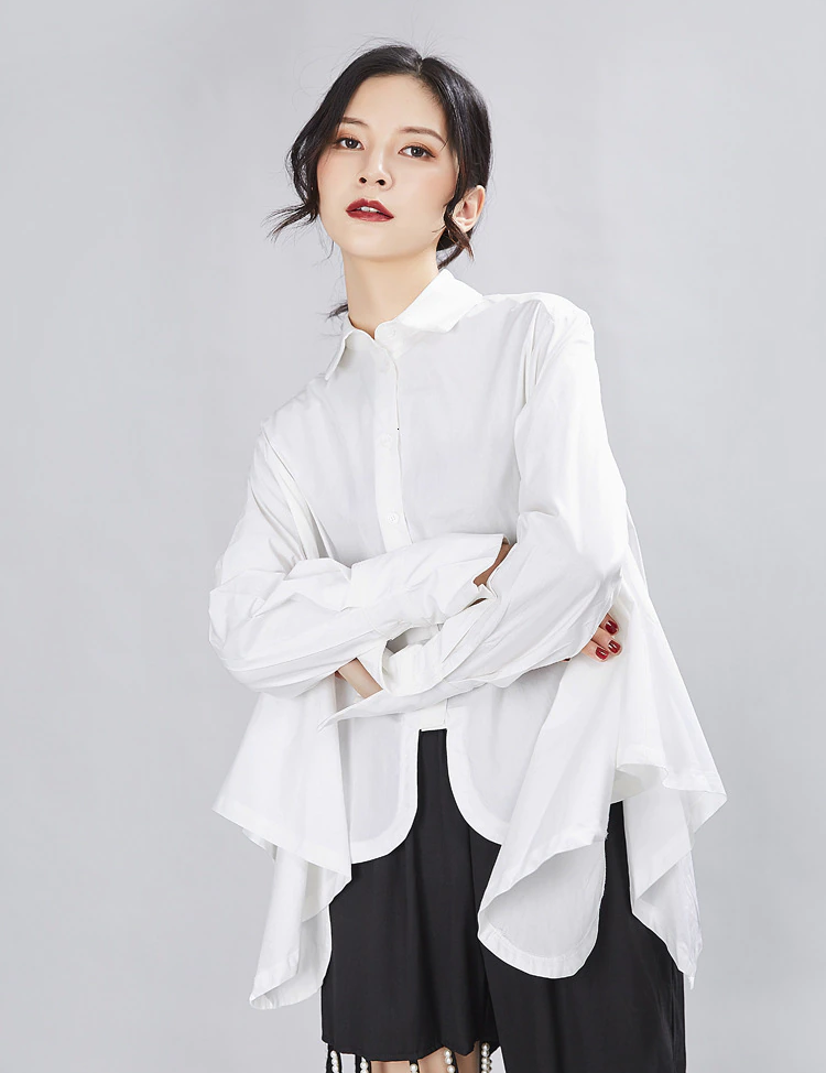 Woman wearing Valcira Irregular Hem Shirt with asymmetric hem and loose fit, showcasing modern style and versatility in white jersey cotton.