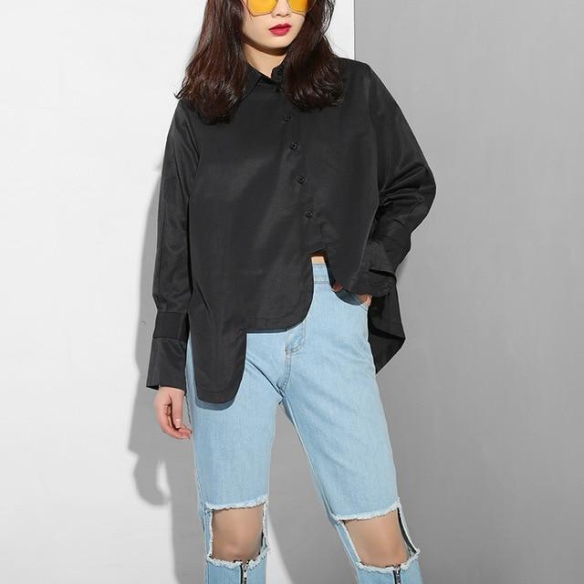Valcira Irregular Hem Shirt in black with classic collar and long sleeves, paired with ripped jeans for a modern, relaxed look.