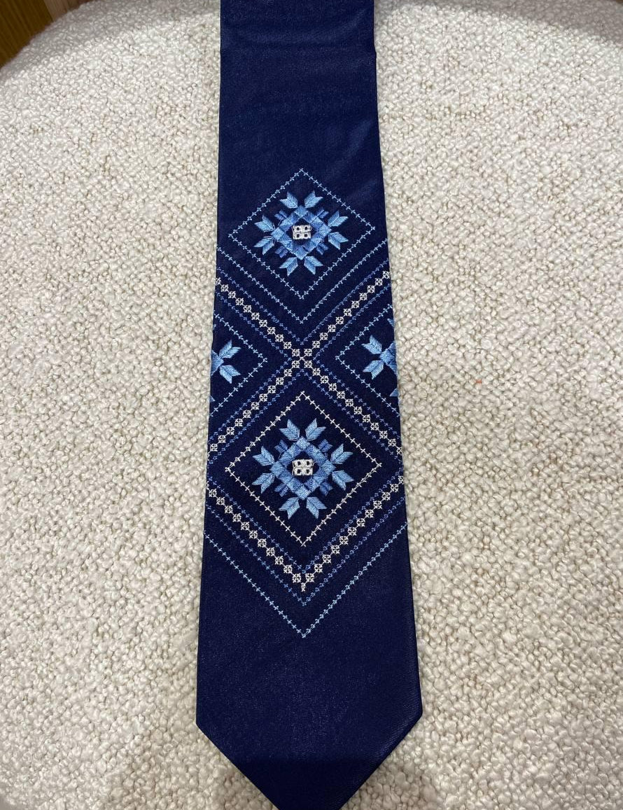Men's blue embroidered tie with Ukrainian folk design on white background, featuring traditional ethnic ornamentation.