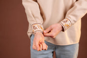 Man adjusting cuff of embroidered Ukrainian Vyshyvanka shirt, showcasing intricate traditional design for special occasions.