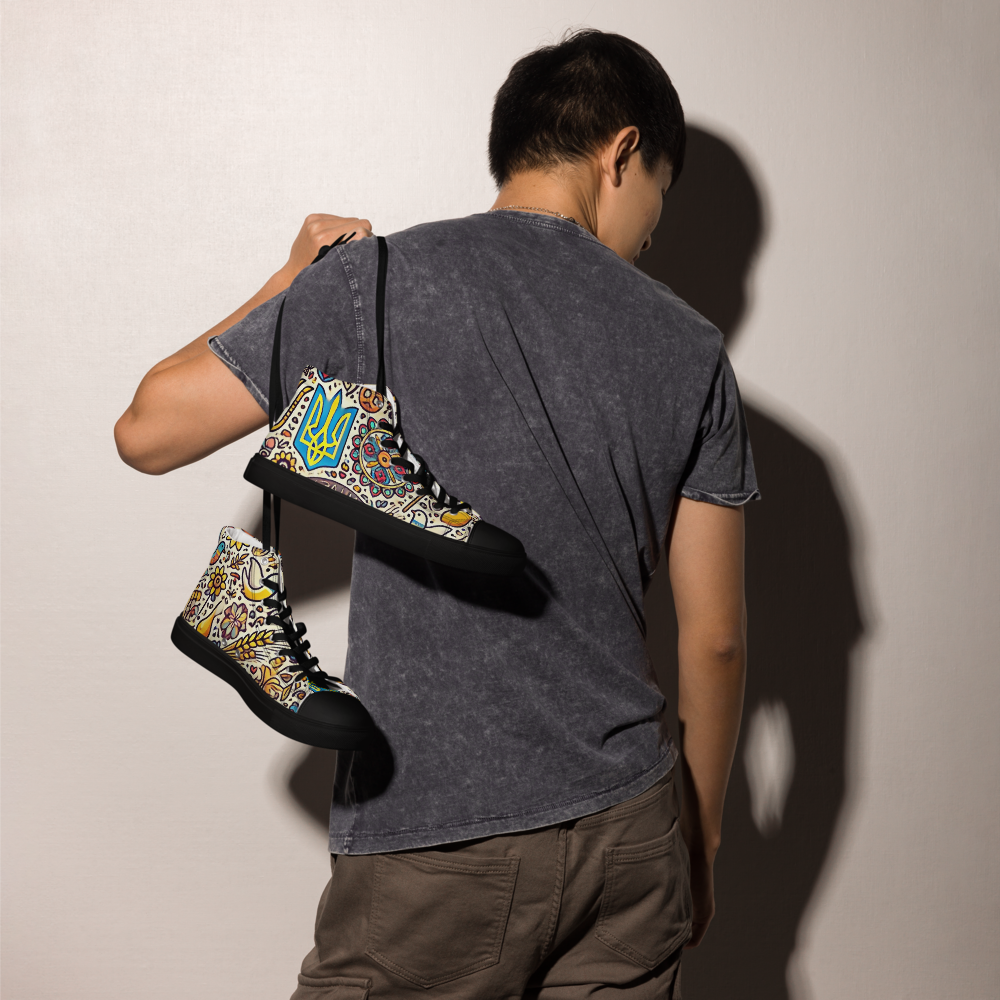 Person holding high top canvas shoes with Ukrainian symbolic design, showcasing trendy and stylish footwear.